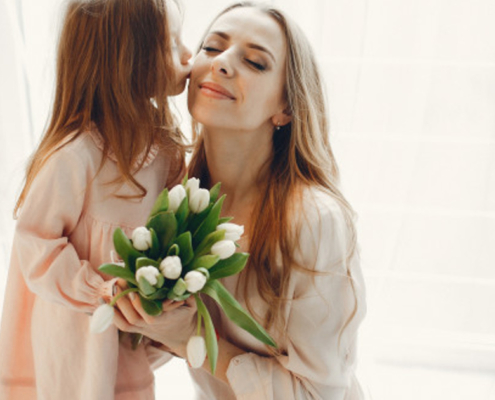 Dia mundial da gentileza: menina presenteando a mãe com flores.